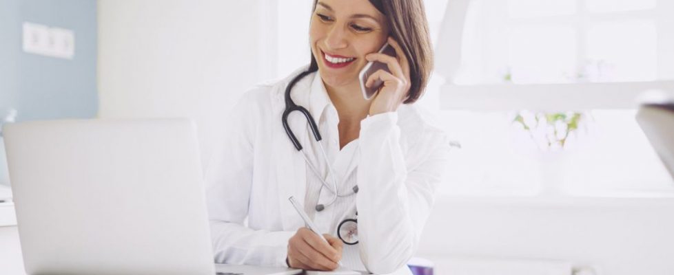 Doctor is on the phone and checking medical records Doctor is on the phone and checking medical records